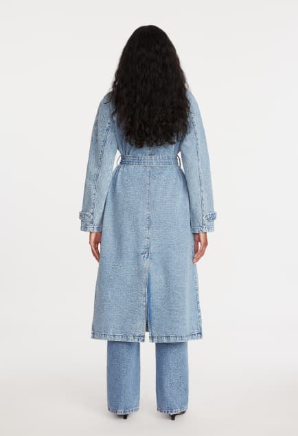 La mannequin porte un trench en denim bleu par-dessus un t-shirt blanc et un jean bleu.