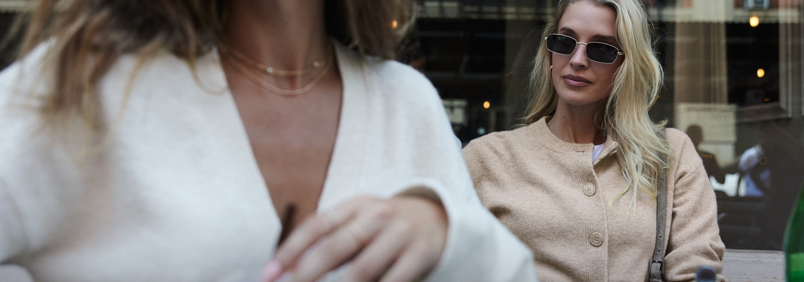 La mannequin de gauche porte un cardigan blanc à col en V et la mannequin de droite porte un chandail beige à col rond.