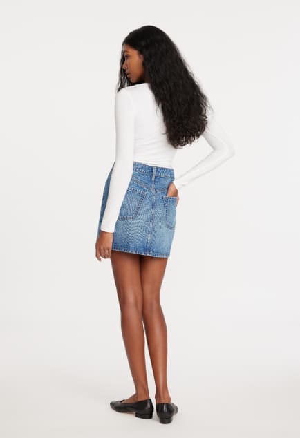 La mannequin porte un t-shirt à manches longues blanc et une jupe maxi en denim bleu.