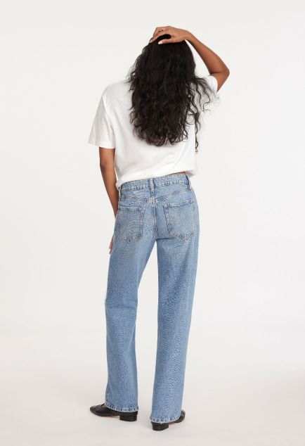 Model is wearing a white T-shirt and blue relaxed straight leg jeans.