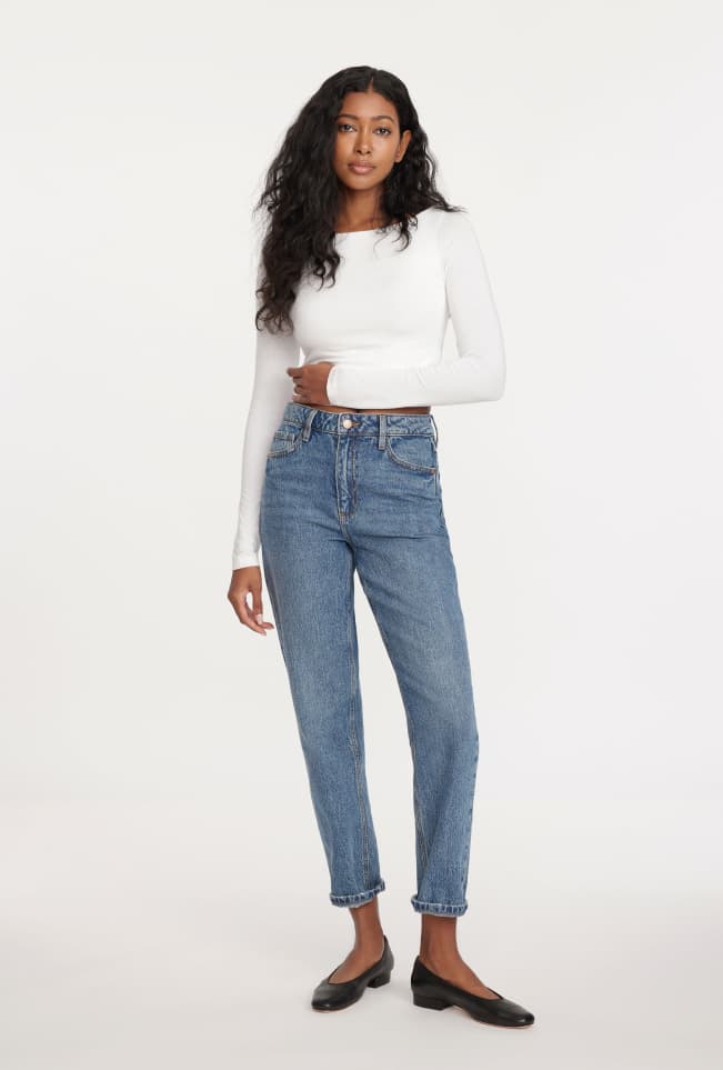 Model is wearing a white T-shirt and blue high-rise mom jeans.