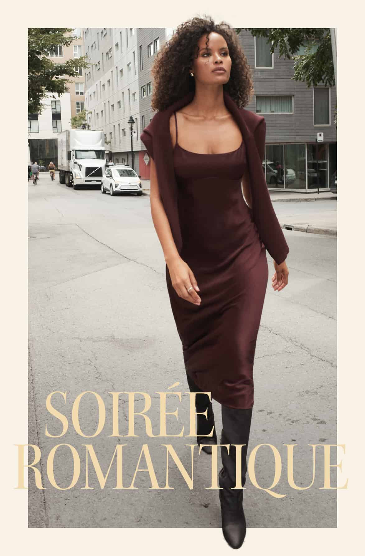 La mannequin porte un cardigan bourgogne par-dessus une robe maxi en satin bourgogne. 