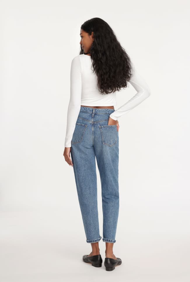 Model is wearing a white T-shirt and blue high-rise mom jeans.