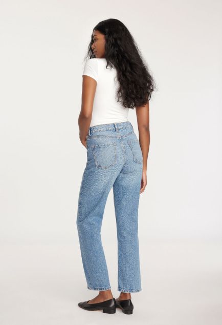 Model is wearing a white shirt and wide leg jeans.