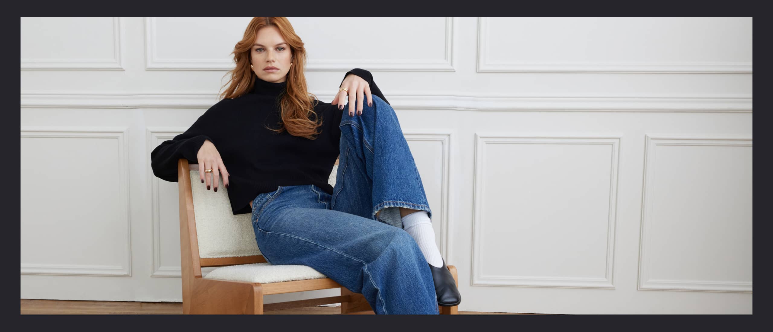 Model is wearing a black turtleneck and blue jeans.