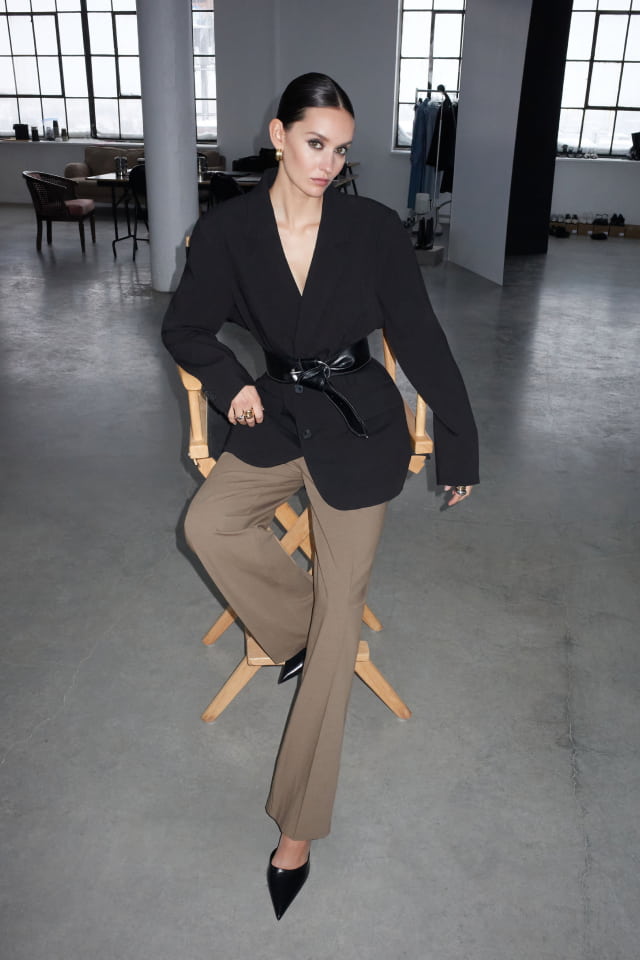 Model is wearing a black blazer and beige pants.