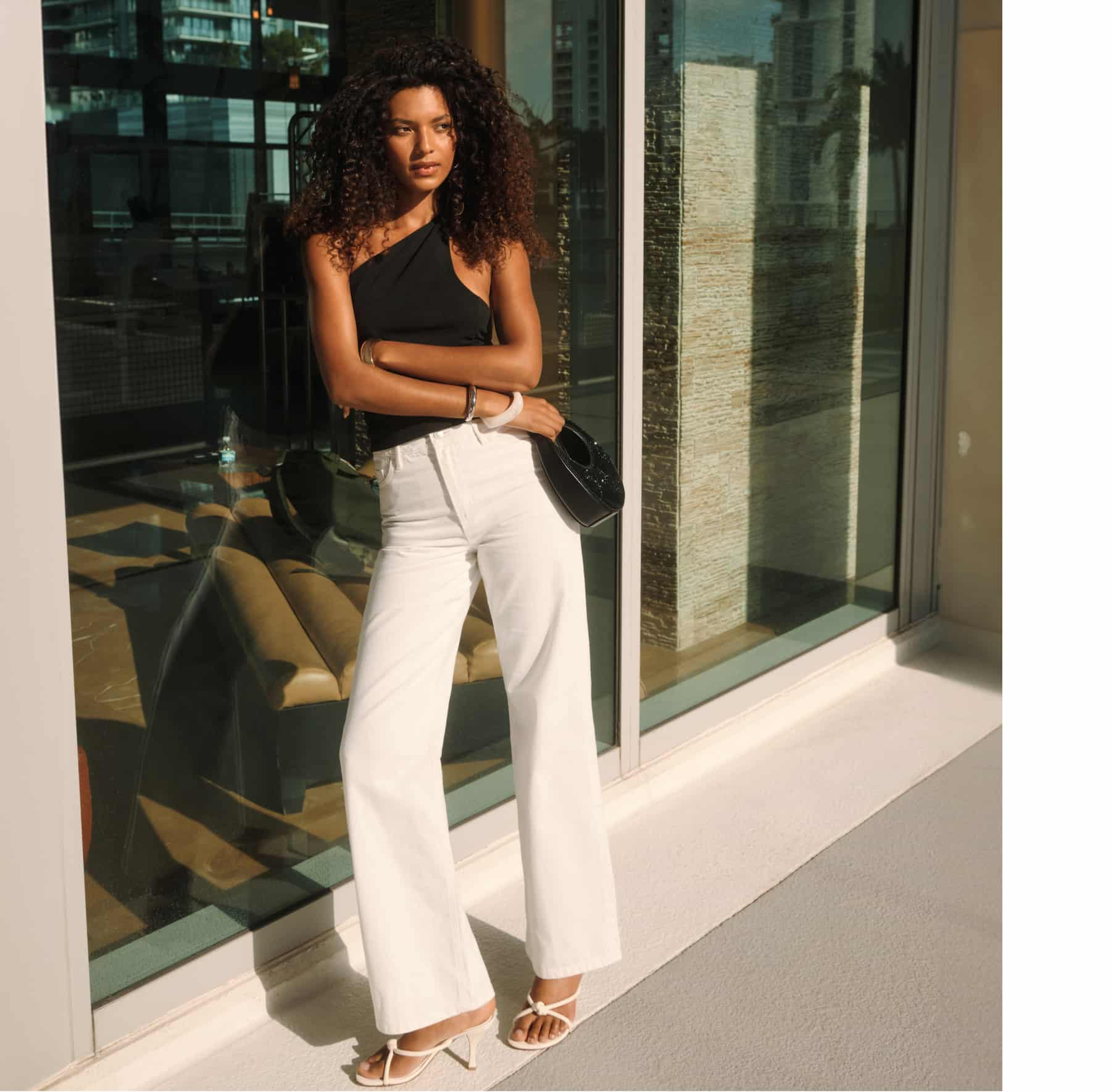 Model is wearing a black one-shoulder knot top and white Heidi wide leg jeans.