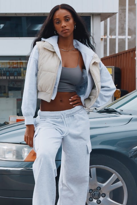 Model wears a white sweat suit with a beige puffer vest and a grey tank top.