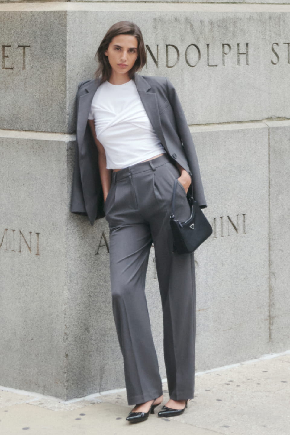 A model wears a grey blazer with matching straight leg pants and a white top.