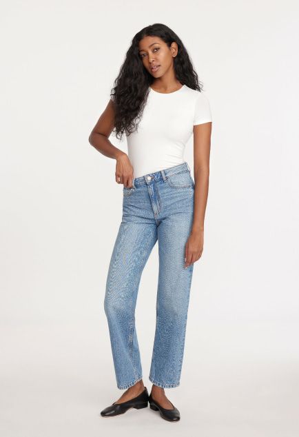 Model is wearing a white shirt and wide leg jeans.