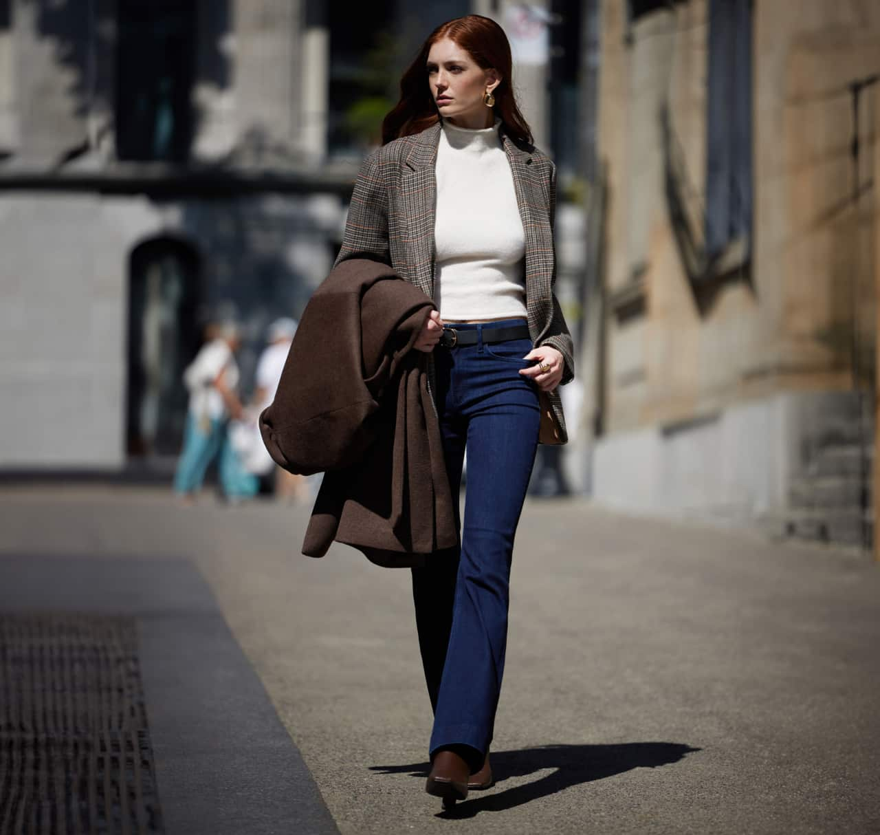 Model is wearing a brown blazer over a white t-shirt and blue jeans.