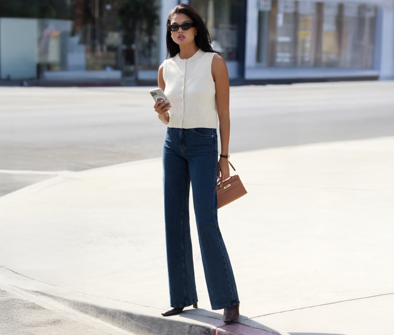 Model is wearing a white button up vest and dark blue jeans.