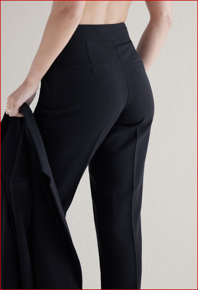 Model is wearing black high waisted pants.