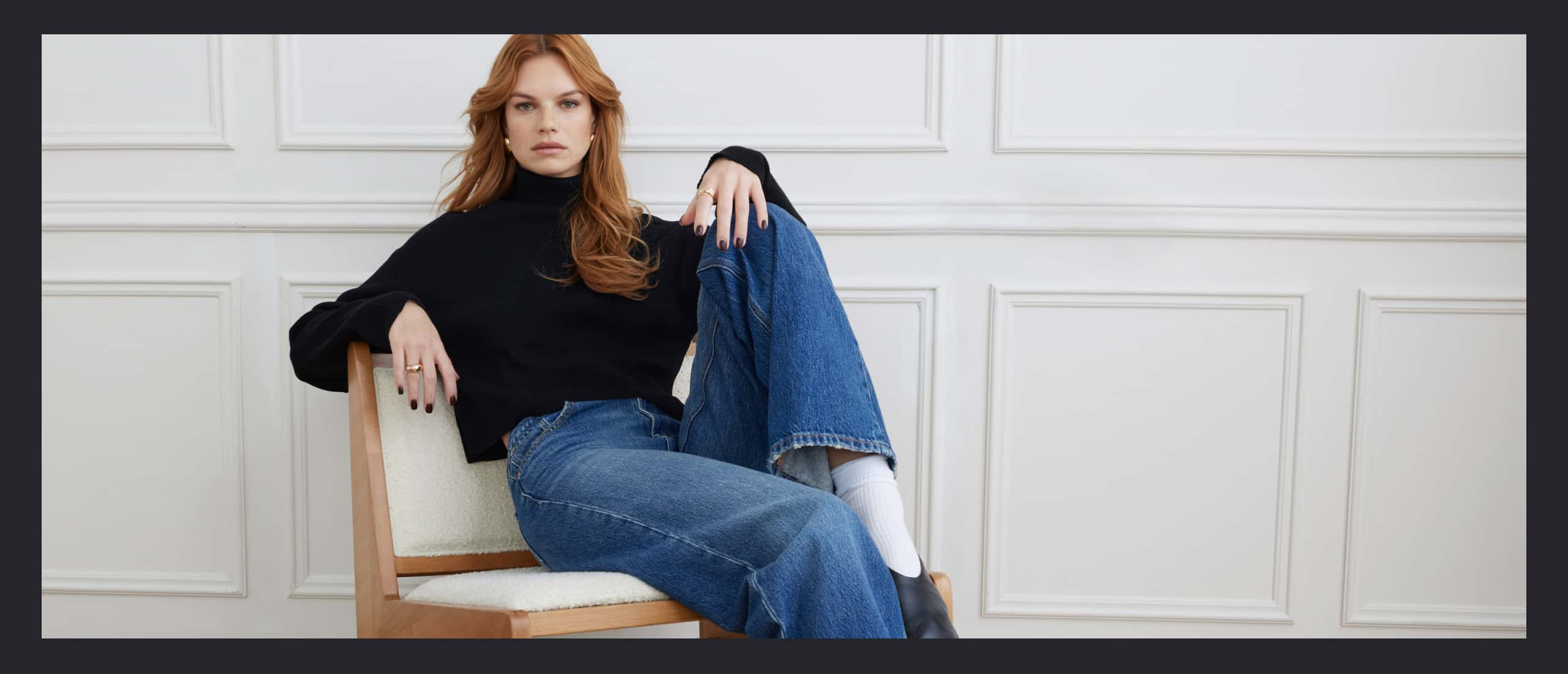 Model is wearing a black turtleneck and blue jeans.